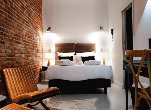 a bedroom with a bed and a brick wall at Hôtel Château Héloïse in Mérélessart