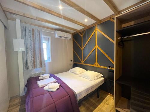 ein kleines Schlafzimmer mit einem Bett mit einer lila Decke in der Unterkunft Camping La Pinède in Calvi