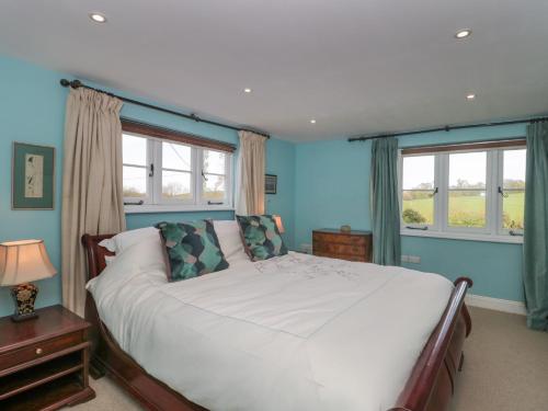 1 dormitorio con 1 cama blanca y 2 ventanas en Brook Cottage, en Sturminster Newton