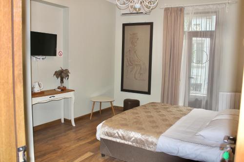 a bedroom with a bed and a desk and a television at Luxor Garden in Batumi