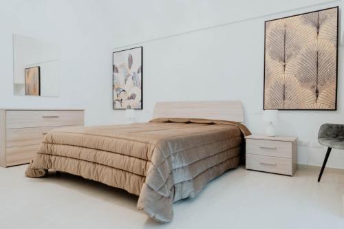 ein weißes Schlafzimmer mit einem Bett und einem Stuhl in der Unterkunft Casa tutti i frutti in Noci