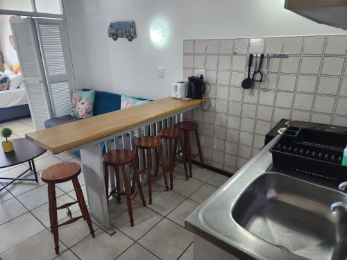 a kitchen with a sink and some bar stools at Driftsands Sea View Flats in Uvongo Beach