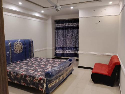a bedroom with a bed and a red chair at Shah Gee Guest House in Islamabad