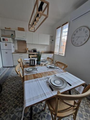 a kitchen with a wooden table with chairs and a clock at Leukif - Appartement T4 Duplex 4* avec Rooftop in Leucate