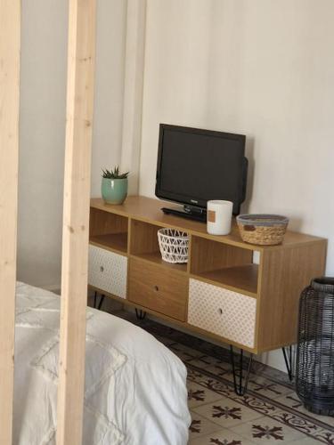 a television on a wooden stand in a bedroom at Leukif - Appartement T4 Duplex 4* avec Rooftop in Leucate
