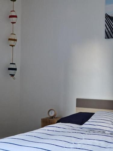 a bedroom with a bed with blue sheets and a clock at Leukif - Appartement T4 Duplex 4* avec Rooftop in Leucate