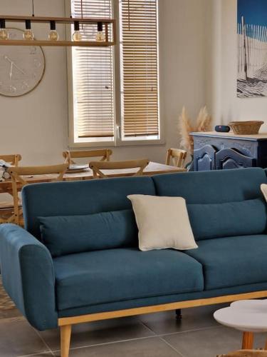 a blue couch with a white pillow in a living room at Leukif - Appartement T4 Duplex 4* avec Rooftop in Leucate