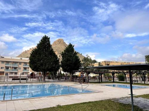 Ático con terraza, piscina y jacuzzi في Villanueva de Río Segura: مسبح كبير بجبل في الخلف
