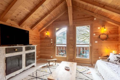 a log cabin living room with a tv and a couch at Auberge du coin in Saint-Colomban-des-Villards