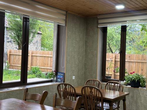 a dining room with tables and chairs and windows at Bala's House in Mestia