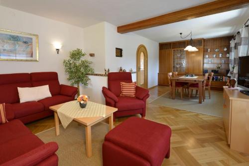 a living room with red furniture and a kitchen at Ferienwohnung Faerber in Reit im Winkl