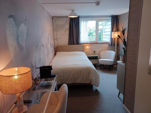 OosterendにあるHotel Dichtbijzeeのベッドとデスクが備わるホテルルームです。