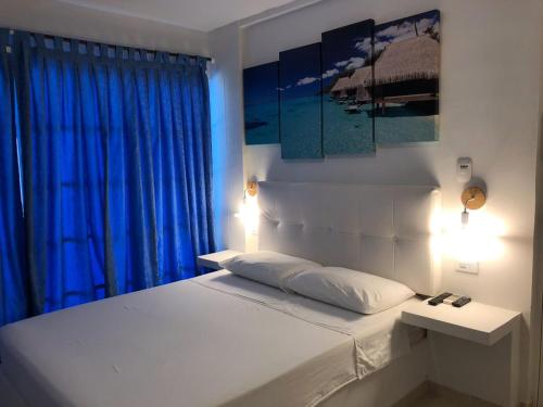 Schlafzimmer mit einem großen Bett und blauen Vorhängen in der Unterkunft Hotel Tropical Inn in Tierra Bomba