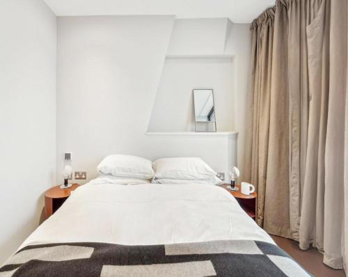 1 dormitorio con 1 cama con sábanas blancas y ventana en Victorian Style in St James, en Londres