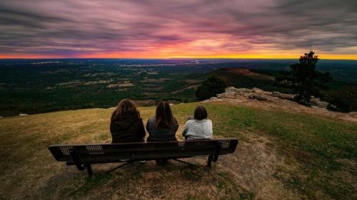 three women sitting on a bench watching the sunset at Amys Place Remolded 4 Bedroom near Arkansas Tech in Russellville