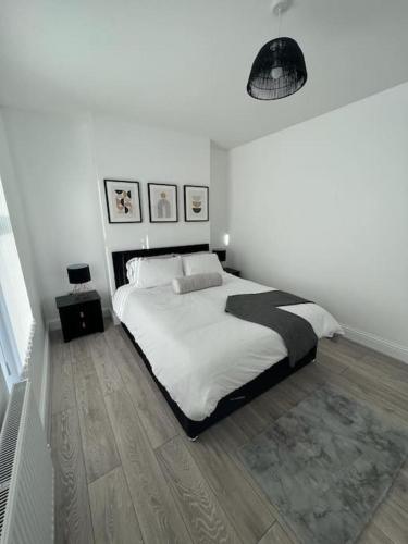 a white bedroom with a bed and a wooden floor at Beautiful Anfield Family Home in Liverpool