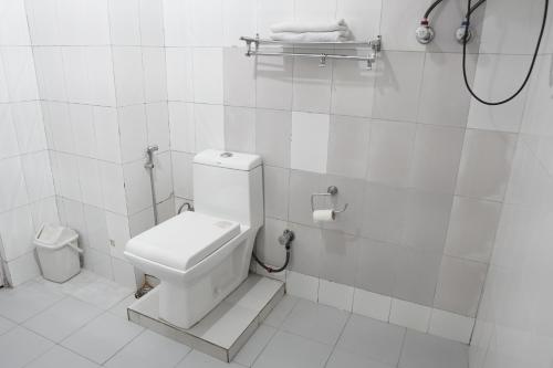 a white bathroom with a toilet and a shower at Ramta Jogi Hotel & Stays in Manāli