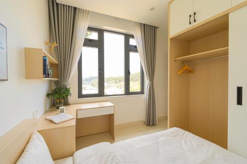 a bedroom with a bed and a desk and a window at Lucia House in Ấp Kim Thạch