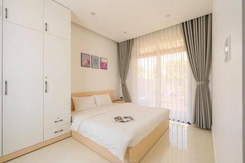 1 dormitorio con cama blanca y ventana en Lucia House, en Ấp Kim Thạch