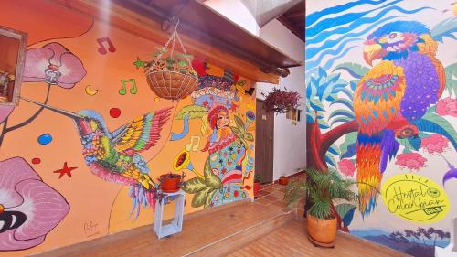 ein Zimmer mit einer bunten Wand, auf der Vögel bemalt sind in der Unterkunft Hostal Colombian Gold in San Gil