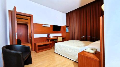 a bedroom with a bed and a desk with a telephone at Bella Italia Palace Hotel in Novara