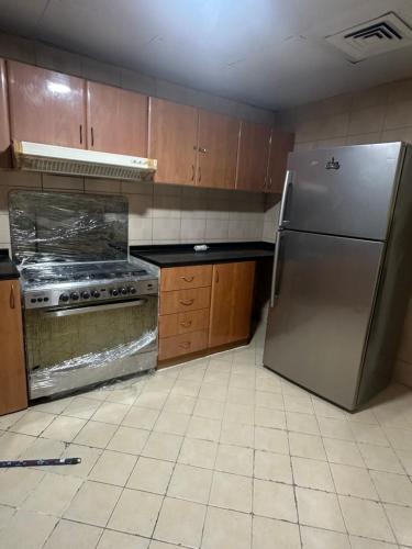 a kitchen with a stainless steel refrigerator and wooden cabinets at Premium Furnished Rooms Your Perfect Stay in Ajman