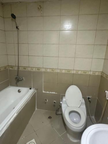 La salle de bains est pourvue de toilettes et d'une baignoire. dans l'établissement Premium Furnished Rooms Your Perfect Stay, à Ajman
