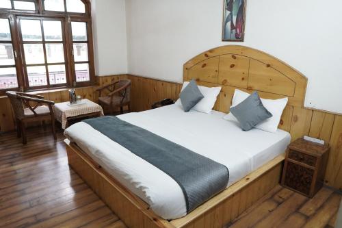 a bedroom with a large bed with a wooden headboard at Ramta Jogi Hotel & Stays in Manāli