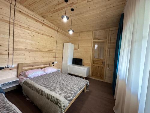 ein Schlafzimmer mit einem Bett in einem Holzzimmer in der Unterkunft Tea Gezruli in Tsinsopʼeli