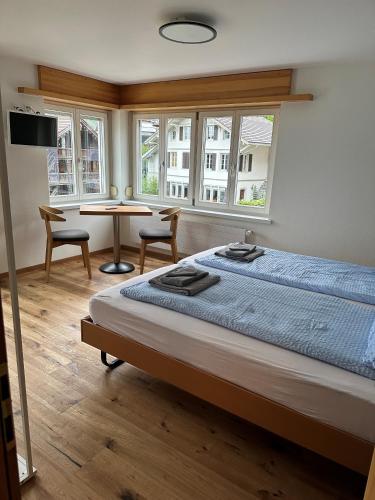 Schlafzimmer mit einem Bett, einem Tisch und Fenstern in der Unterkunft Hotel WALZ in Brienz