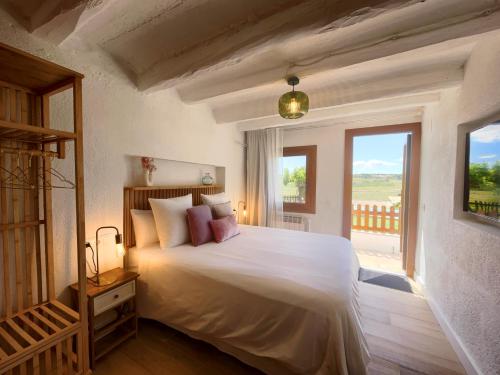 Schlafzimmer mit einem großen weißen Bett und einem Balkon in der Unterkunft Bed & Breakfast Wine & Cooking Penedès in Pla del Panadés