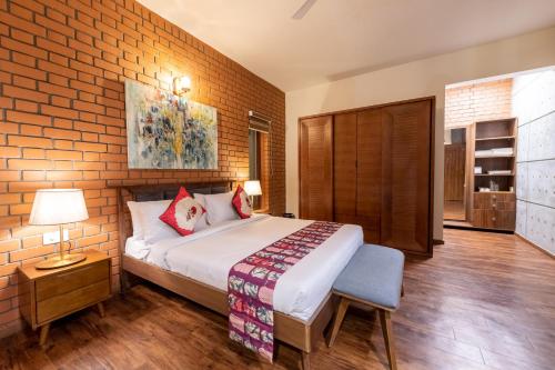 a bedroom with a bed and a brick wall at Asta in Ooty