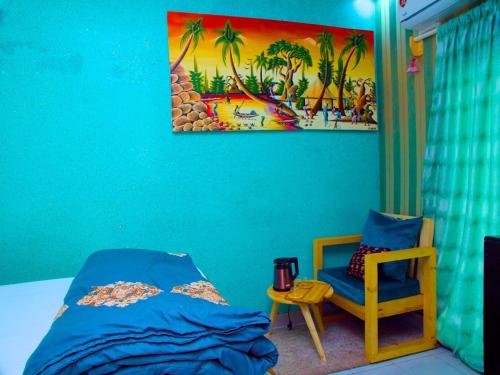 - une chambre dotée d'un mur bleu avec un lit et une chaise dans l'établissement Dakar International House, à Dakar