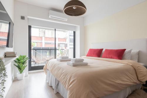 Un dormitorio blanco con una cama grande con almohadas rojas en Fliphaus Zapiola 2300 - Lux Aparts 'a' Belgrano en Buenos Aires