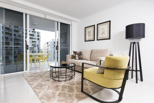 a living room with a yellow chair and a couch at Riviera Mackay in Mackay