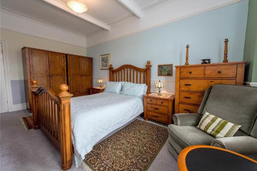 a bedroom with a bed and a couch and a chair at The Strand Hotel in Bournemouth