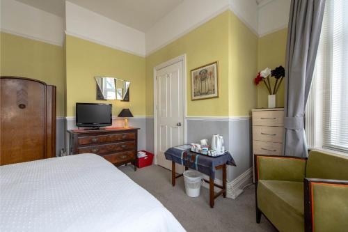 ボーンマスにあるThe Strand Hotelのベッドルーム(ベッド1台、テレビ、椅子付)