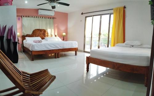a bedroom with two beds and a large window at Casa Gacela Cozumel in Cozumel