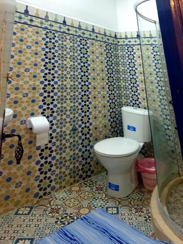 a bathroom with a toilet and a tiled wall at Riad Casa Youssef in Chefchaouene