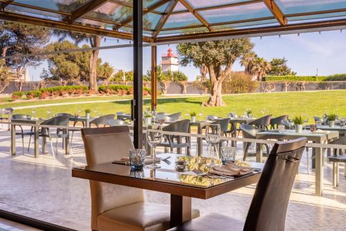 a restaurant with tables and chairs with a view of a park at Vila Gale Cascais in Cascais