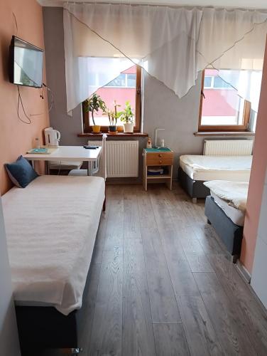 a room with two beds and a desk and two windows at Noclegi Centrum in Jelenia Góra