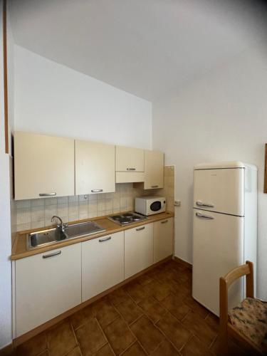 a kitchen with white cabinets and a white refrigerator at Residence La Scogliera in Alassio