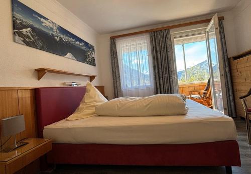 Schlafzimmer mit einem Bett und einem großen Fenster in der Unterkunft Pension Bavaria in Mittenwald