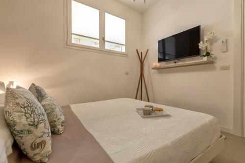 a white bedroom with a bed and a flat screen tv at Luxury Sofia Home Alghero in Alghero