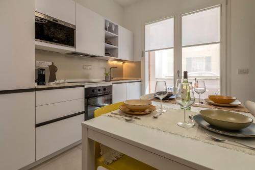 a kitchen with white cabinets and a table with wine glasses at Luxury Sofia Home Alghero in Alghero