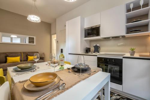 a kitchen with a table with bowls and wine glasses on it at Luxury Sofia Home Alghero in Alghero