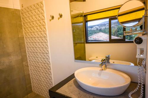 a bathroom with a sink and a mirror and a shower at Hotel & Spa - Caney campestre Villa de Leiva by MH in Villa de Leyva