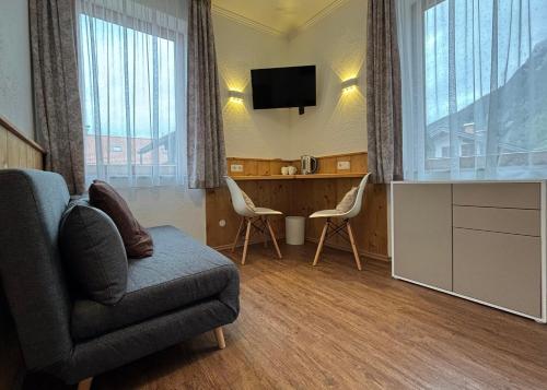 a living room with a couch and a desk and a television at Pension Bavaria in Mittenwald