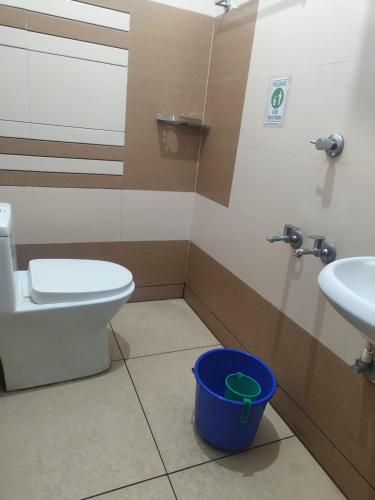 a bathroom with a toilet and a sink and a blue bucket at THEKKUMPURAM RESIDENCY in Kondotti