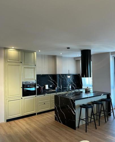 a kitchen with black marble counter tops and a kitchen island at The Boulevard Bliss in Tirana